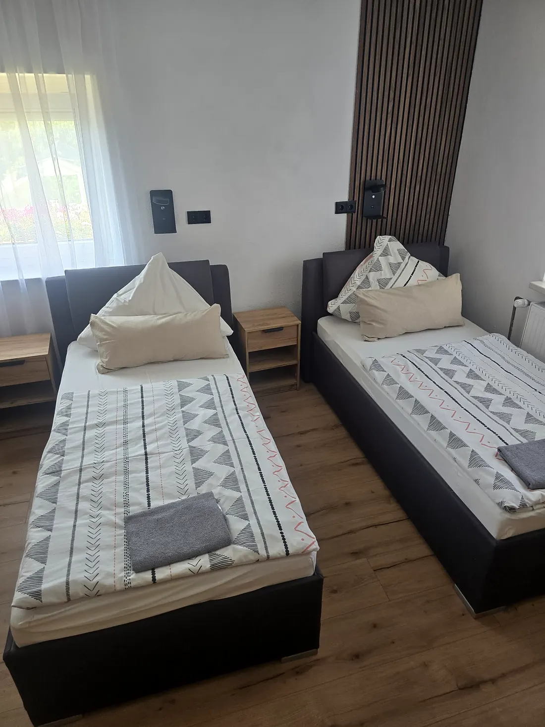 Schlafzimmer in Wohnung 1 mit zwei Einzelbetten und Holzlamellenwand