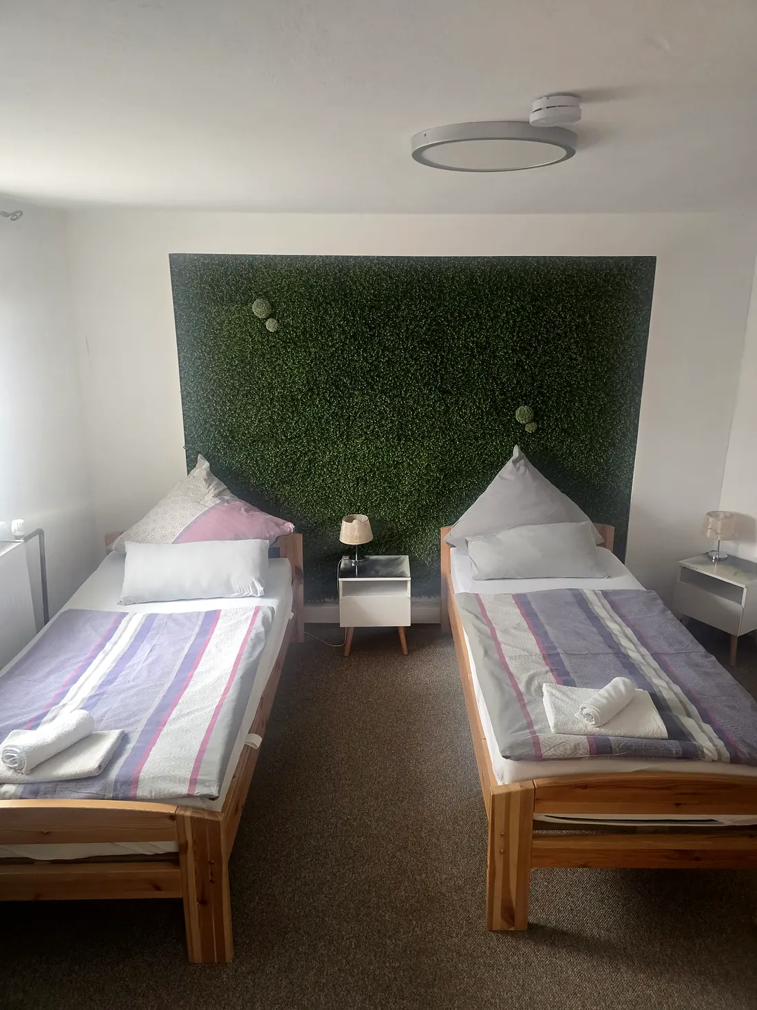Schlafzimmer in Wohnung 2 mit begrünter Wand hinter den Betten