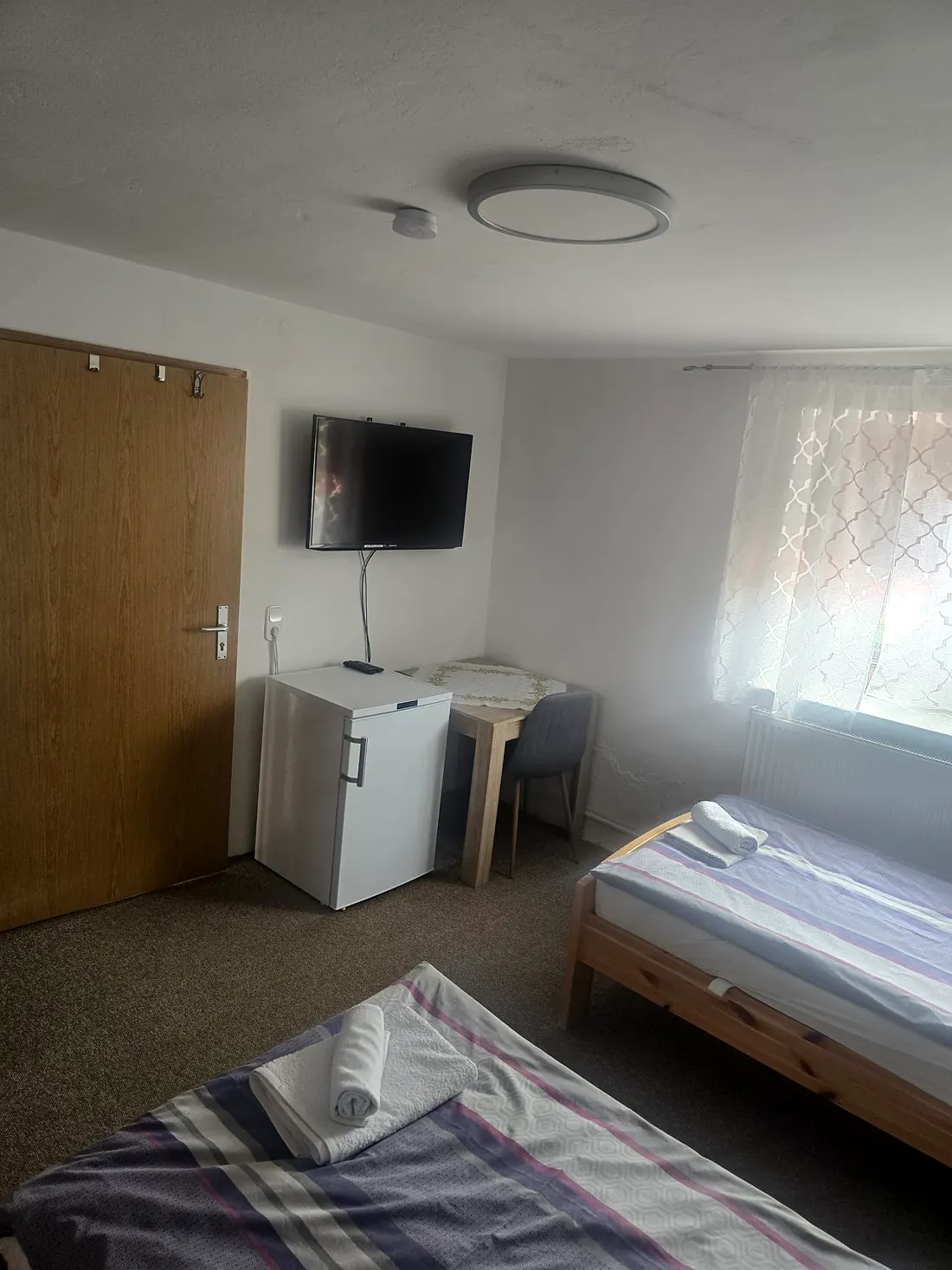 Schlafzimmer in Wohnung 2 mit Fernseher, Kühlschrank und Esstisch